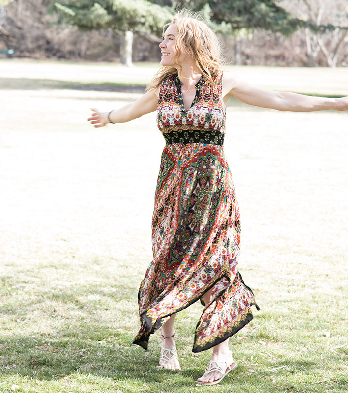 Life Coach Betsy Jensen dancing in a dress with arms spread out