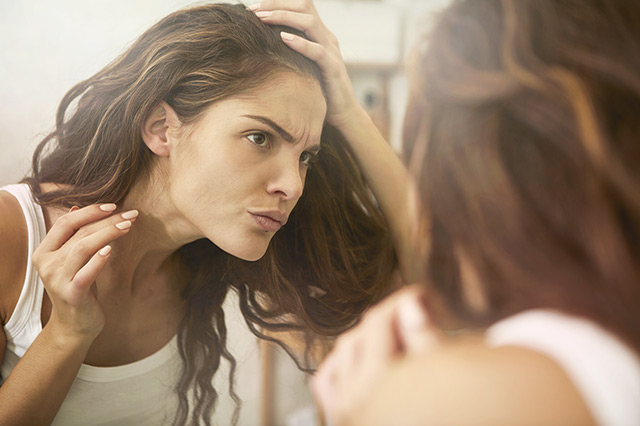 Beautiful brown hair woman looking at herself critically in the mirror