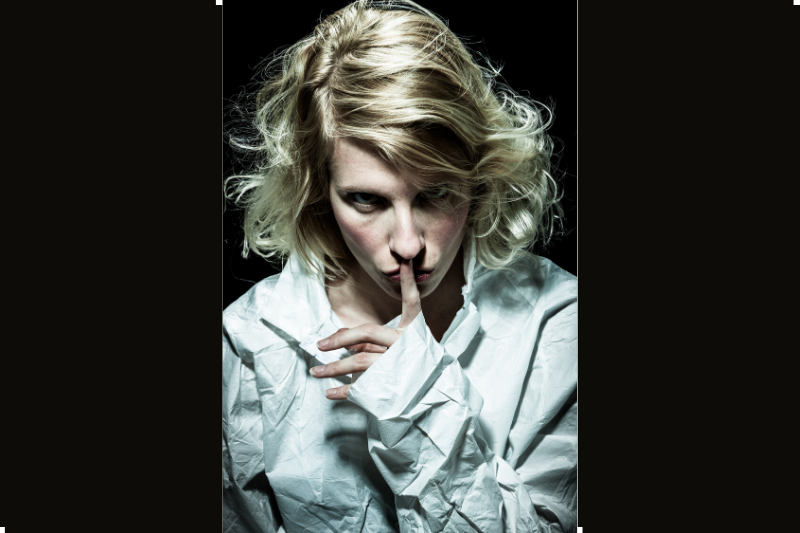 Woman with finger on her lips as a gesture of silence