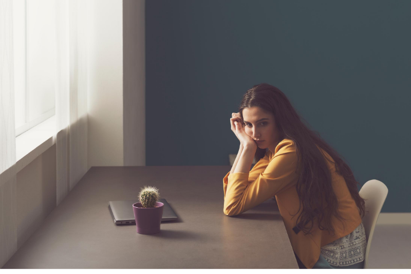 woman looking sad and lonely sitting at a desk