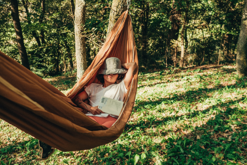 woman in hammock in woods asleep with hat on face